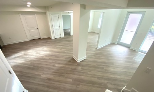 large room with white walls, windows, and wood-style flooring
