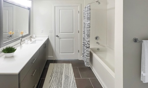 a bathroom with a white door, shower and large sink and mirror