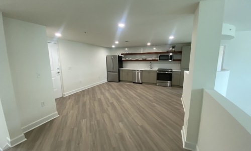 large open space with a kitchen in the background featuring stainless steel appliances